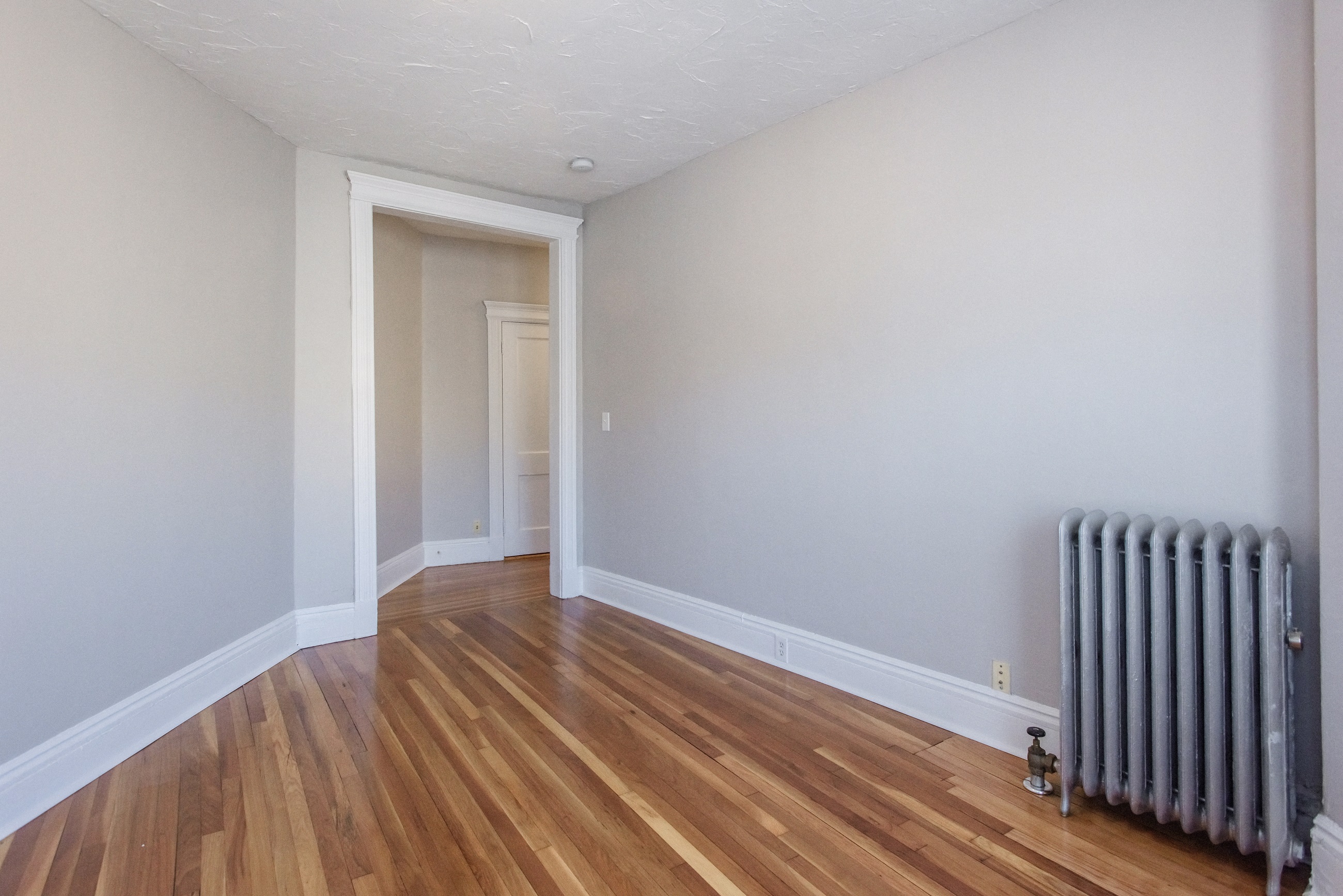 the living room of a house with a radiator and wooden floors